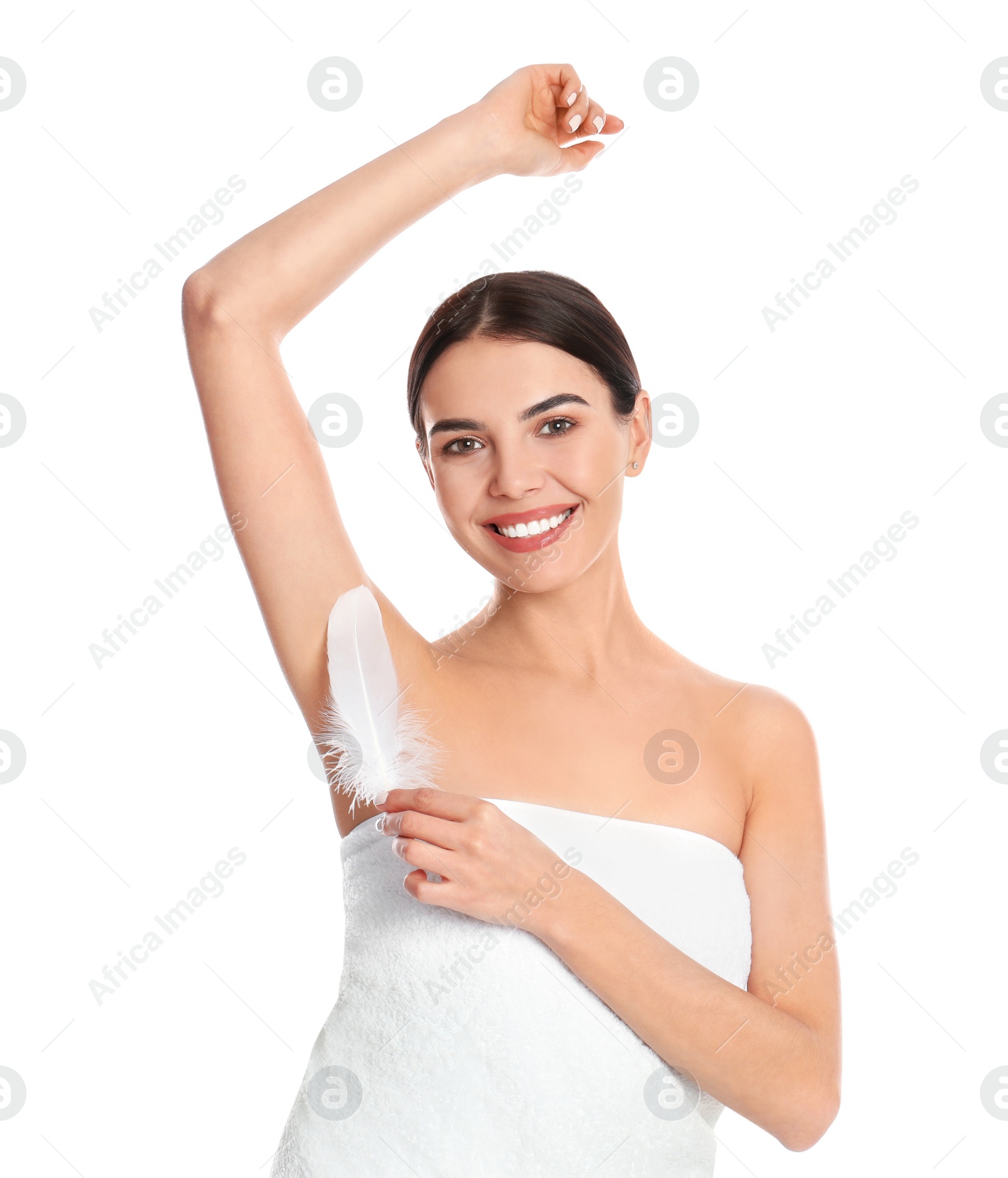 Photo of Young woman touching armpit with feather after epilation procedure on white background