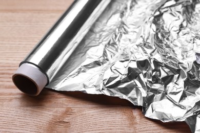 Photo of Roll of aluminum foil on wooden table, closeup