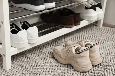Photo of Orthopedic insoles in shoes on rug near rack, closeup