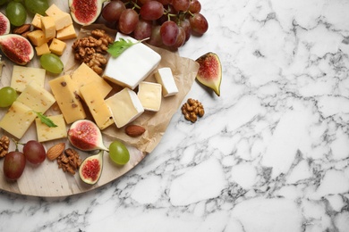 Photo of Set of different snacks with ripe figs served on marble table, flat lay. Space for text