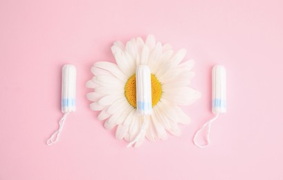 Tampons and chamomile on light pink background, flat lay