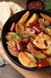 Photo of Delicious baked potato with thin dry smoked sausages, onion and dill in bowl on table, closeup