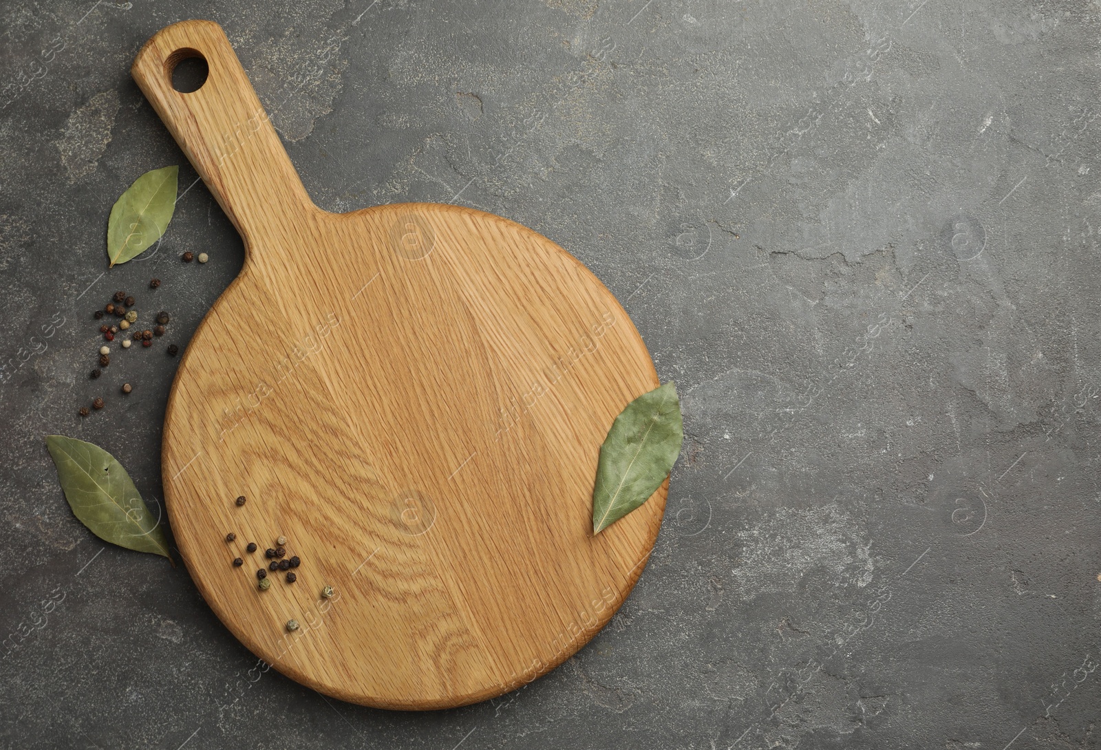 Photo of Cutting board, pepper and bay leaves on grey table, flat lay. Space for text