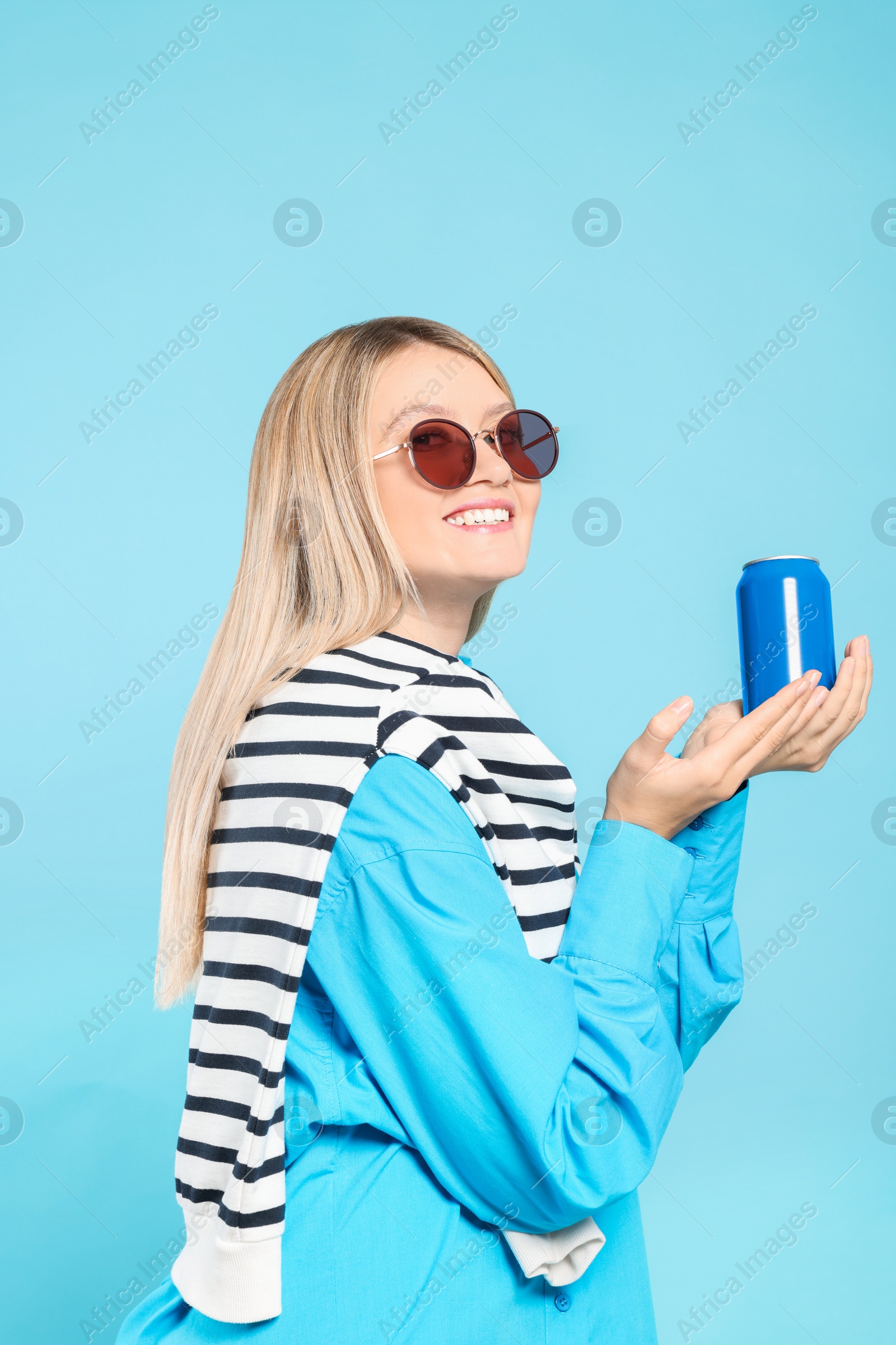 Photo of Beautiful happy woman holding beverage can on light blue background