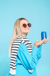 Photo of Beautiful happy woman holding beverage can on light blue background