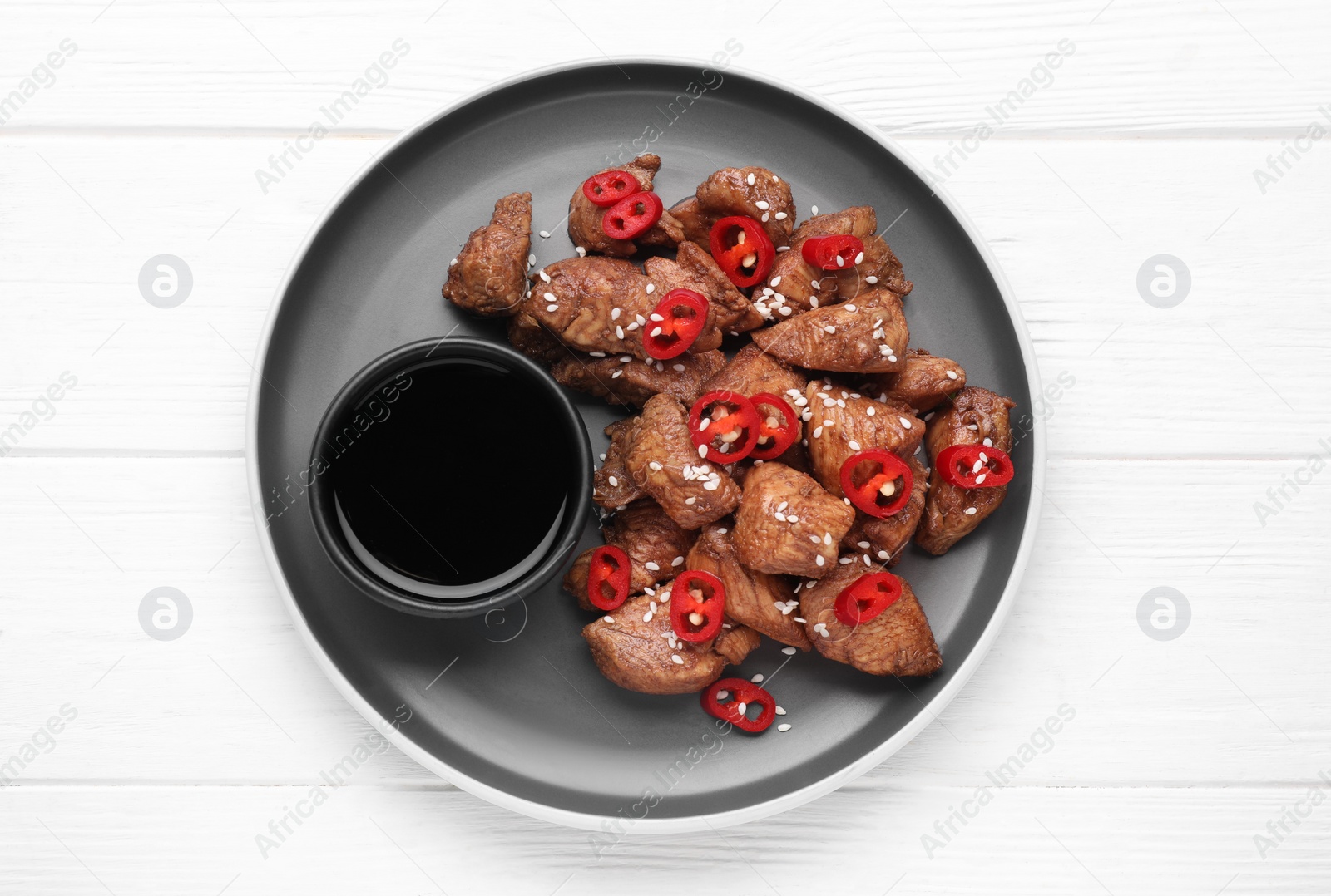 Photo of Plate with tasty soy sauce and roasted meat on white wooden table, top view