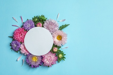 Photo of Beautiful aster flowers with sheet of paper on color background, top view. Space for text