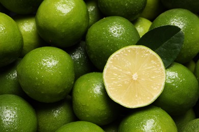 Photo of Fresh limes and leaf with water drops as background, top view