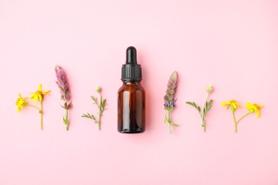 Photo of Bottle of essential oil and wildflowers on color background, flat lay