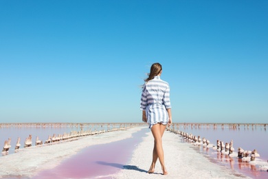 Beautiful woman posing near pink lake on summer day