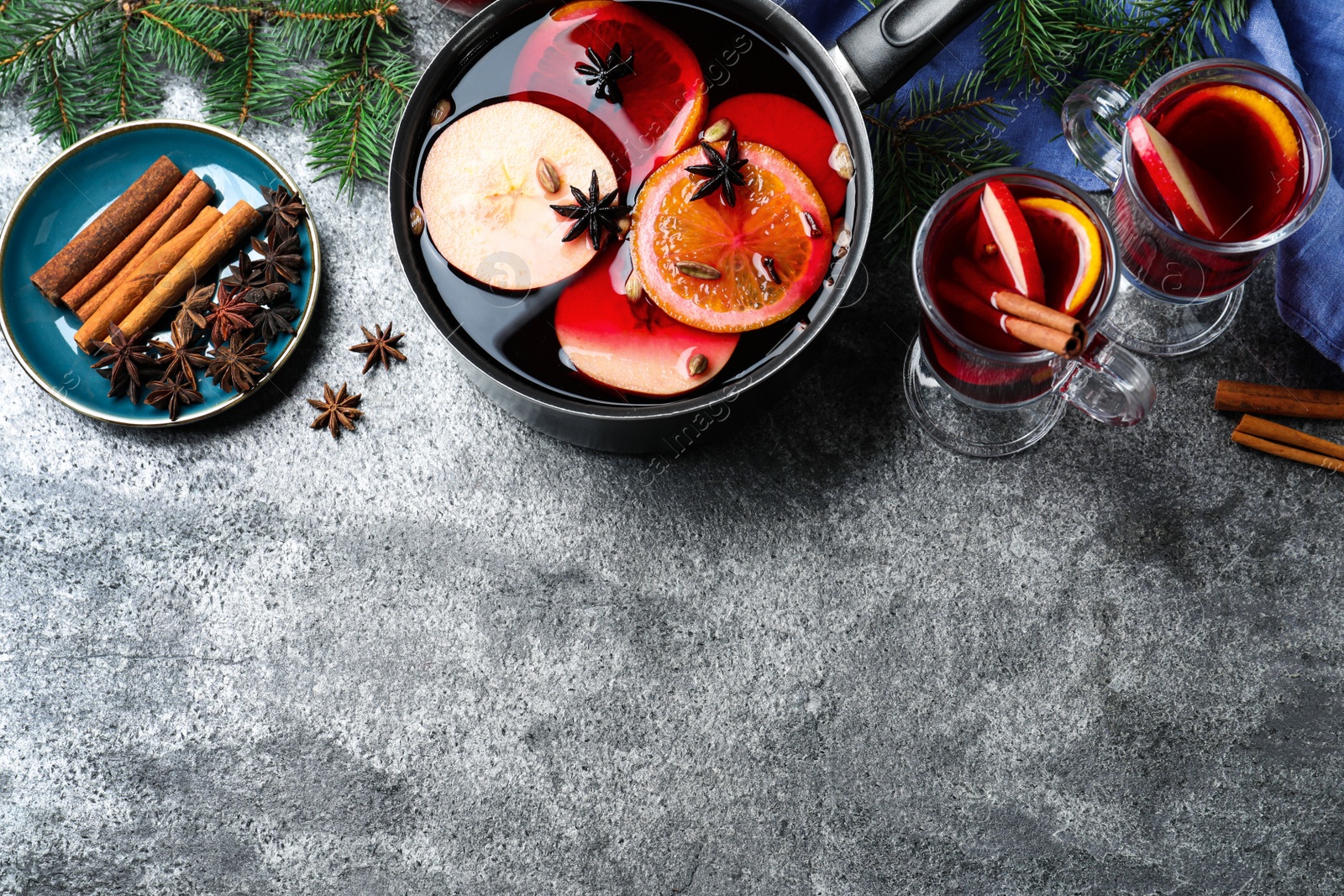 Photo of Delicious mulled wine and ingredients on grey table, flat lay. Space for text