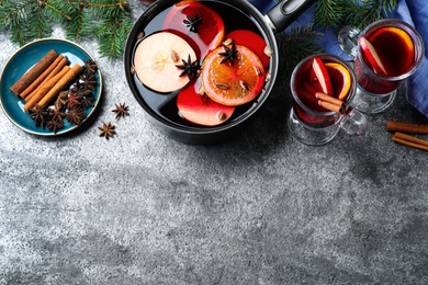 Photo of Delicious mulled wine and ingredients on grey table, flat lay. Space for text