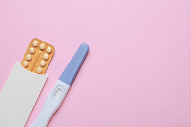 Photo of Birth control pills and pregnancy test on pink background, top view. Space for text