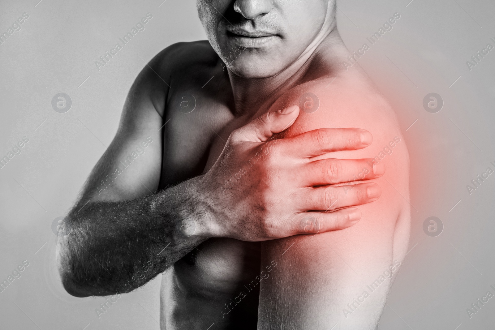 Image of Man suffering from shoulder pain, closeup. Black and white photo 
