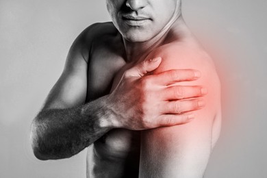 Man suffering from shoulder pain, closeup. Black and white photo 