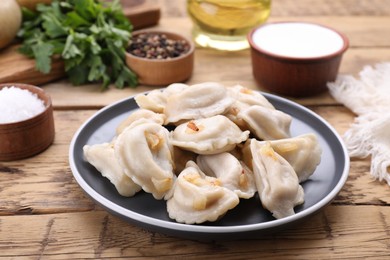Photo of Delicious dumplings (varenyky) with potatoes and onion on wooden table