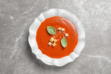 Photo of Plate with fresh homemade tomato soup on grey background, top view