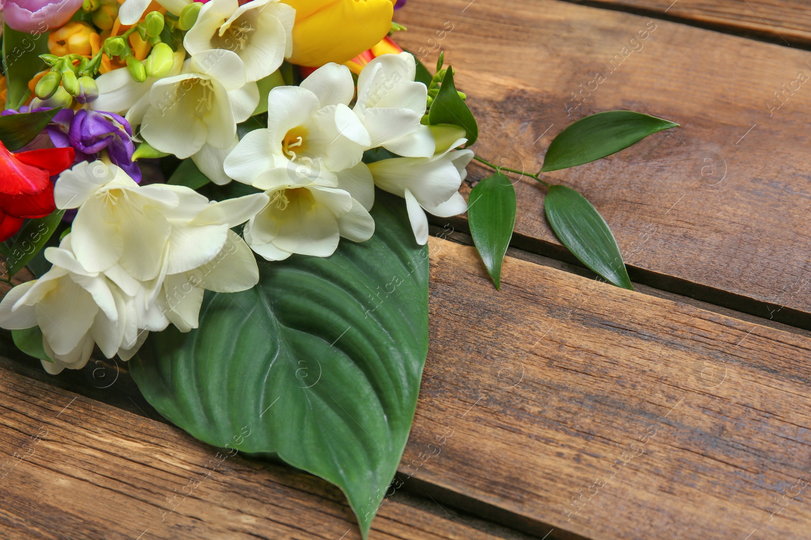 Photo of Beautiful freesia bouquet on wooden background