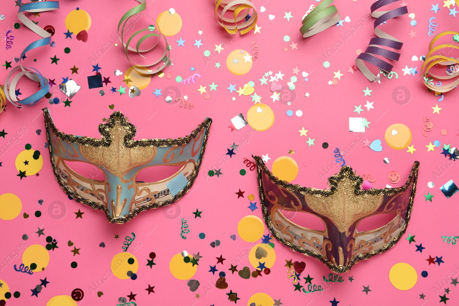 Photo of Beautiful carnival masks and party decor on pink background, flat lay