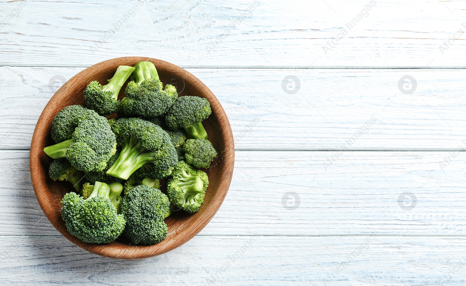 Photo of Plate of fresh green broccoli on white wooden table, top view. Space for text