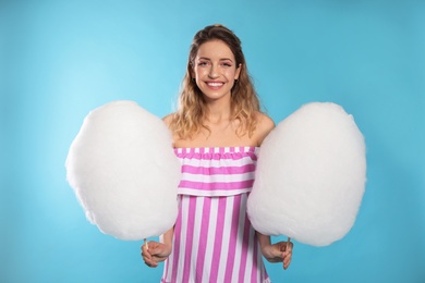 Portrait of pretty young woman with cotton candy on blue background