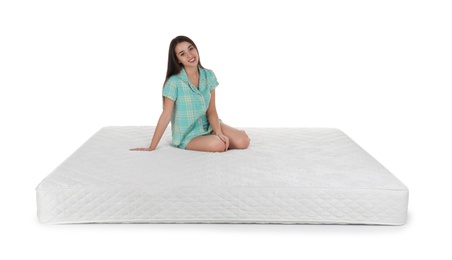 Photo of Young woman sitting on mattress against white background