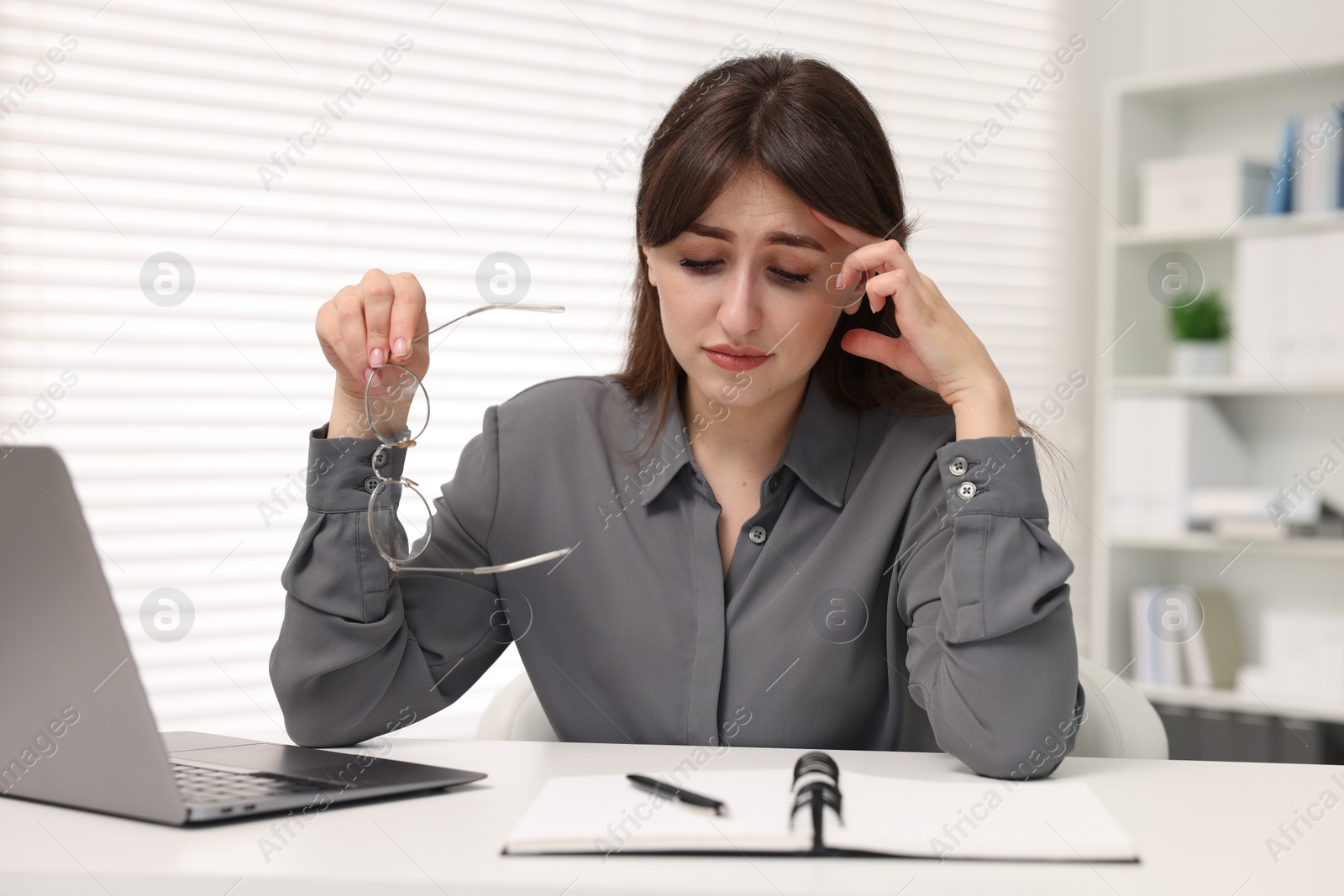 Photo of Overwhelmed woman sitting at table with laptop in office