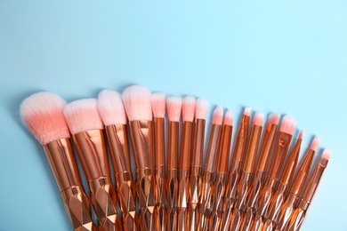 Flat lay composition with set of makeup brushes on light blue background