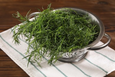 Photo of Colander with fresh tarragon leaves on wooden table