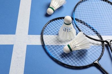 Feather badminton shuttlecocks and rackets on blue background. Space for text