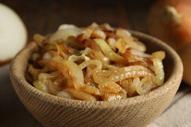 Tasty fried onion in wooden bowl, closeup