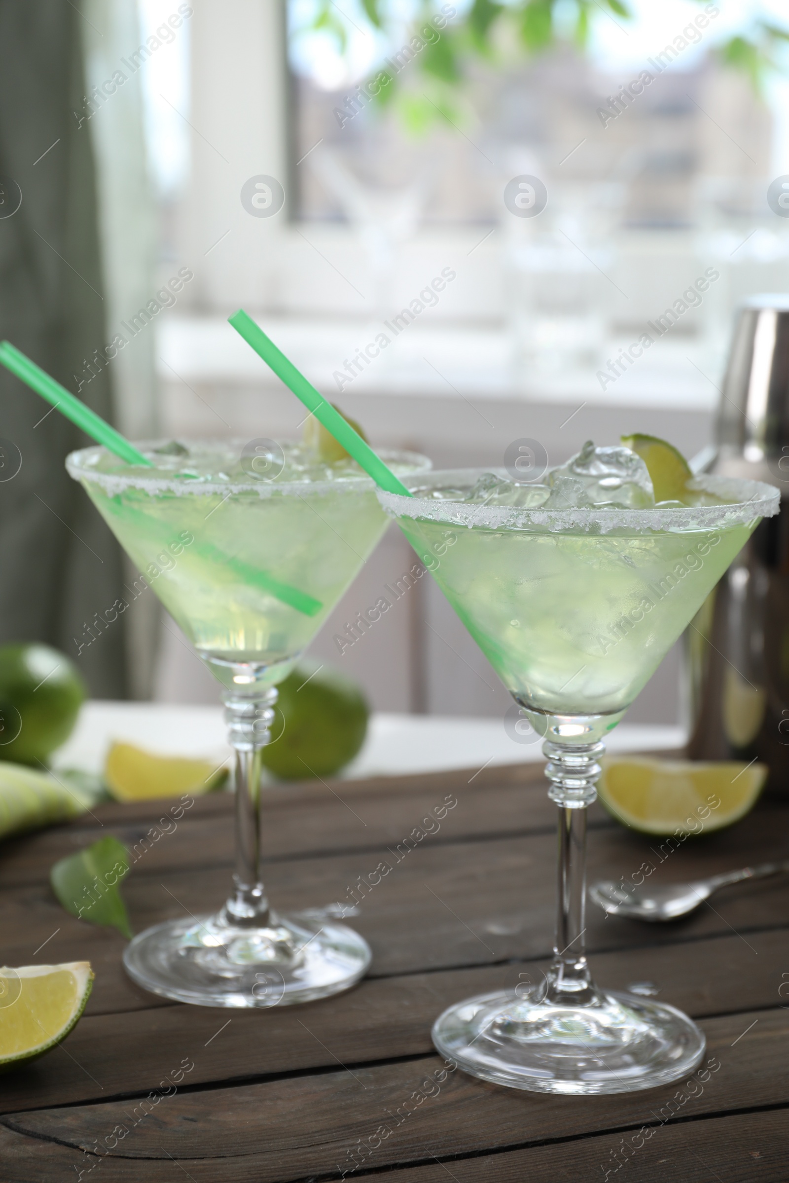 Photo of Delicious Margarita cocktail in glasses and lime on wooden table