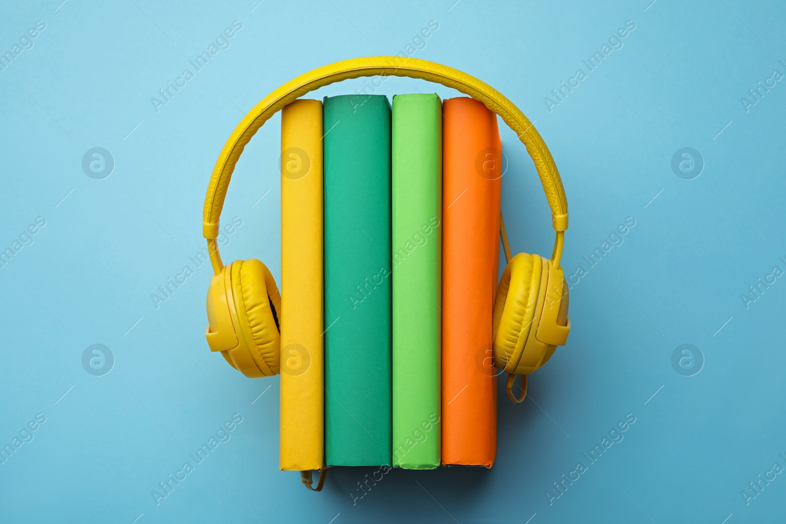 Photo of Books and modern headphones on light blue background, top view