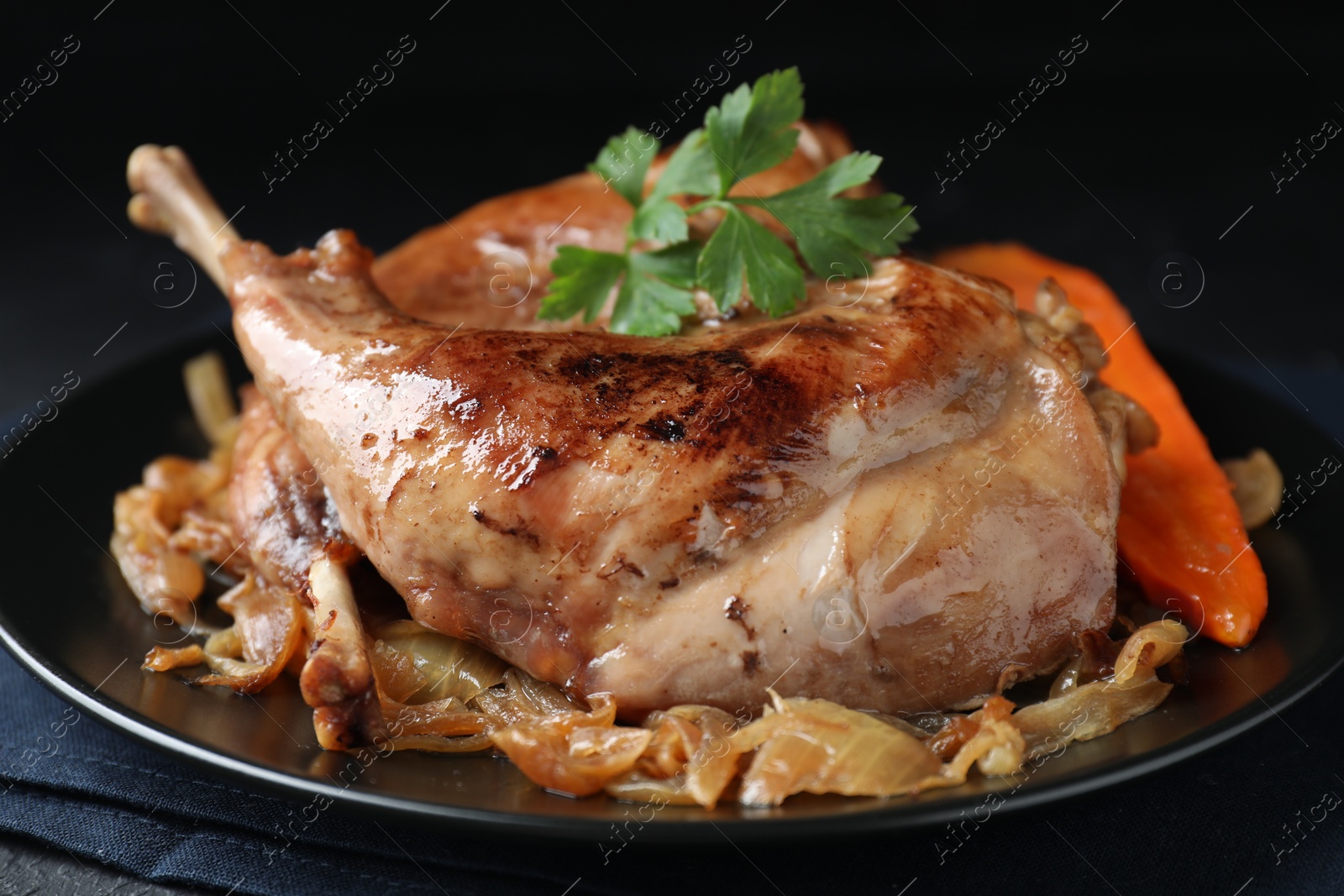 Photo of Tasty cooked rabbit meat with vegetables and parsley on table, closeup