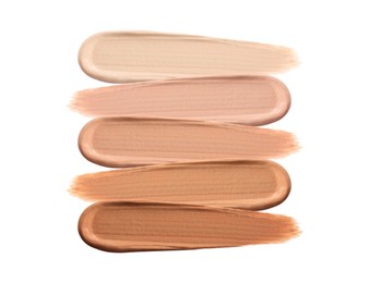 Different shades of liquid skin foundation on white background, top view