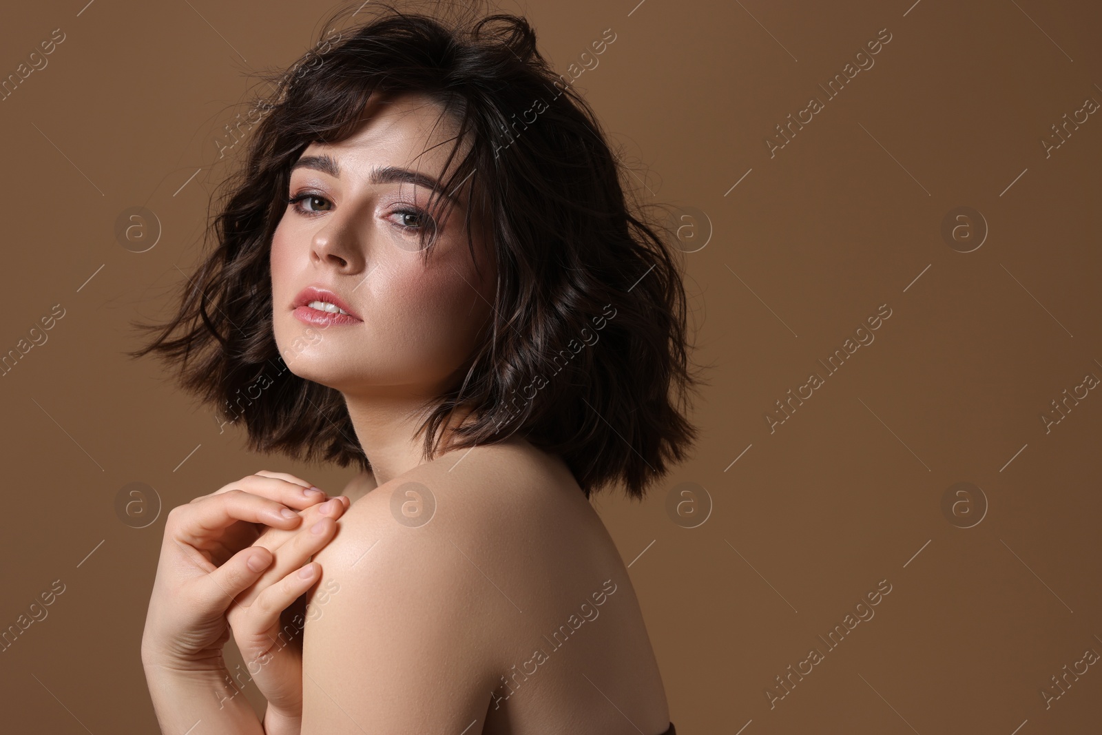 Photo of Portrait of beautiful young woman with wavy hairstyle on brown background. Space for text