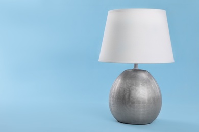 Photo of Stylish new night lamp on light blue background. Space for text