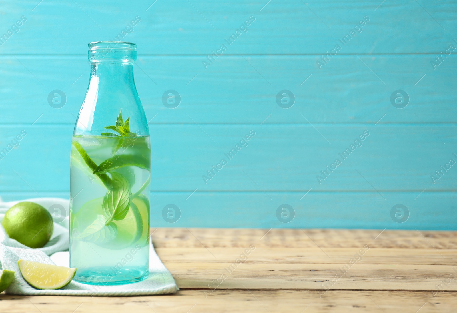 Photo of Natural lemonade with lime in bottle on wooden table