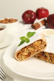 Photo of Delicious strudel with apples, nuts and raisins on white table