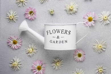 Photo of Watering can and beautiful flowers on light grey background, flat lay