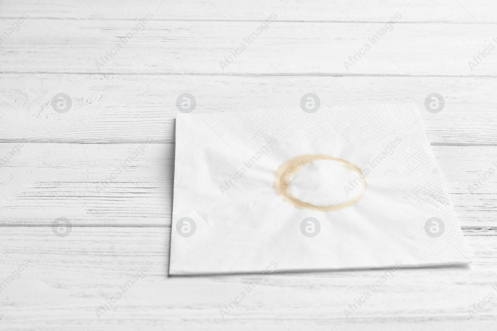 Photo of Dirty napkin with coffee stain on wooden background. Space for text