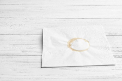 Dirty napkin with coffee stain on wooden background. Space for text