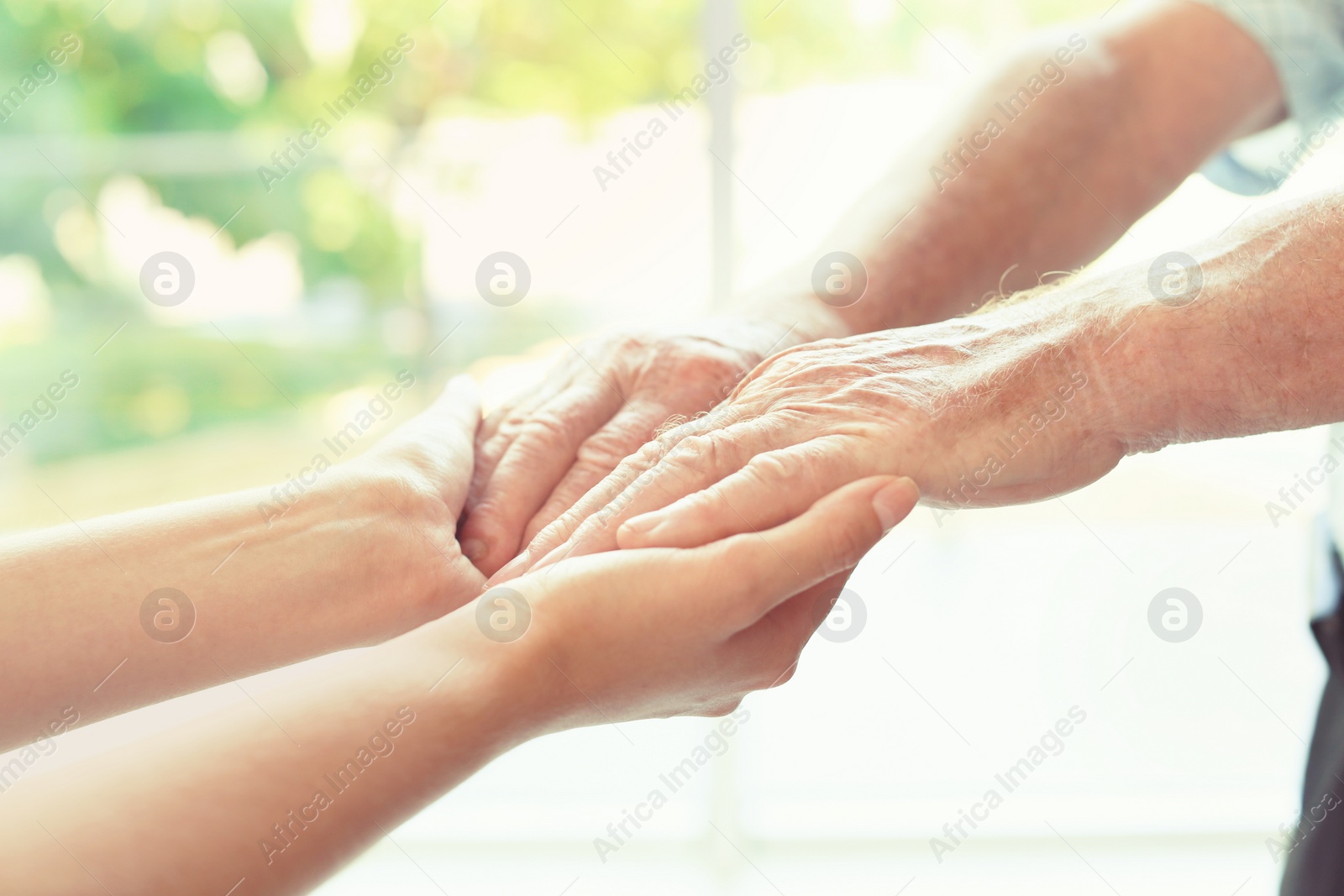 Photo of Helping hands on blurred background, closeup. Elderly care concept