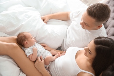 Happy couple with their newborn baby on bed