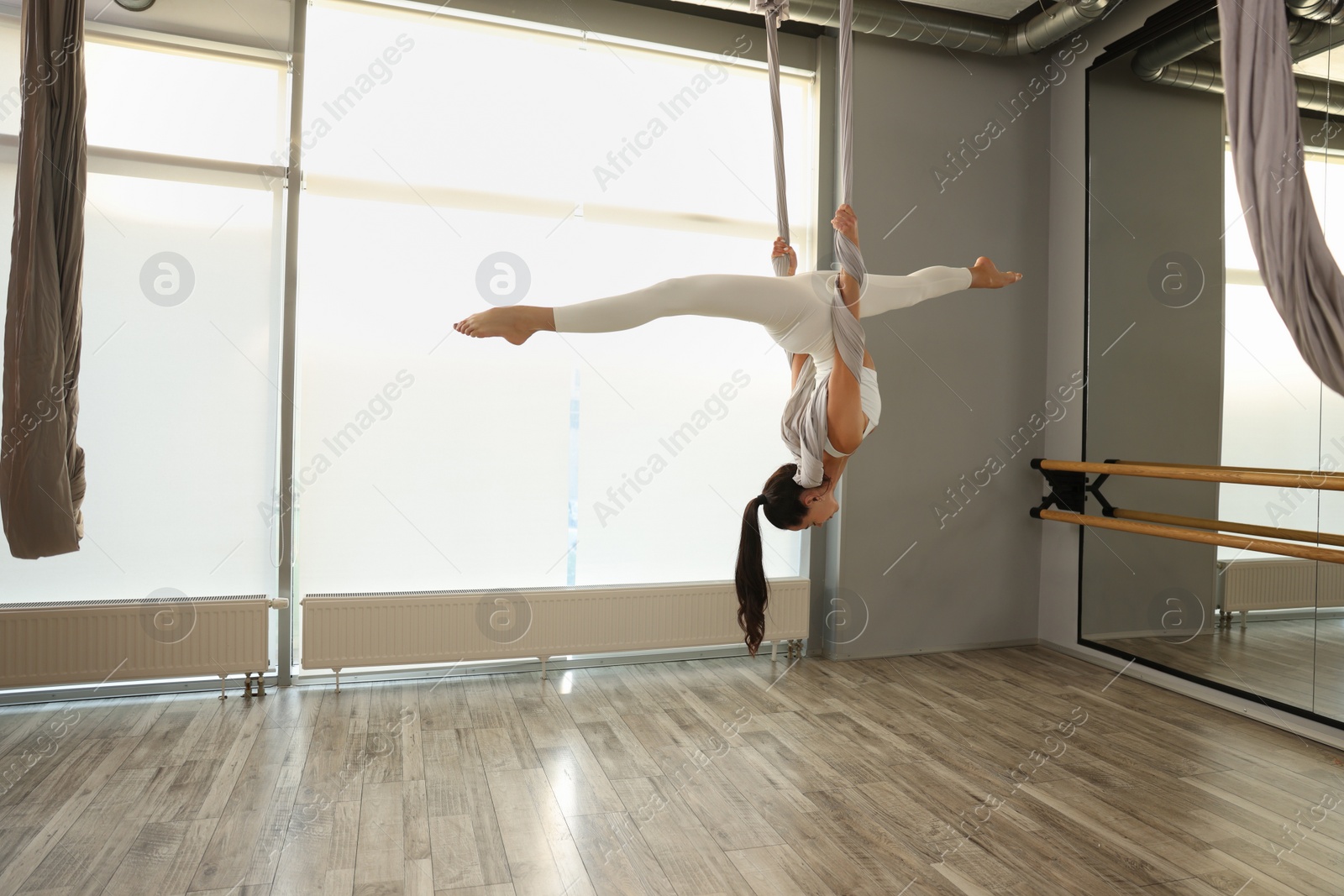 Photo of Young woman practicing fly yoga on hammock in studio