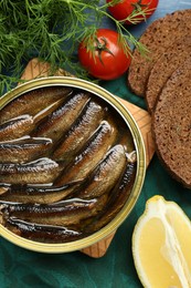 Photo of Tin can with tasty sprats served on table, flat lay