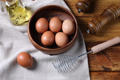 Photo of Metal whisk, raw eggs in bowl and spices on table, flat lay