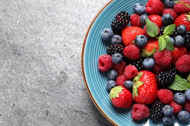 Many different fresh ripe berries in plate on grey table, top view. Space for text