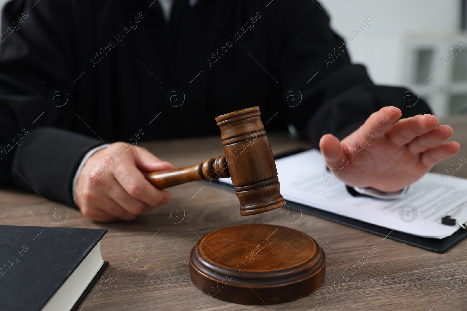 Photo of Judge with gavel and papers sitting at wooden table, closeup