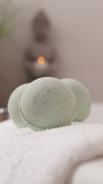 Photo of Towel with bath bombs on tub indoors, closeup